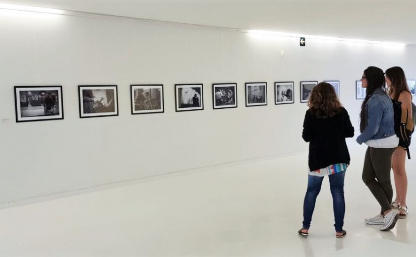 Esta imagen muestra el Hall de la Facultad de Comunicación de la Universidad San Jorge donde se encuentran las dos estudiantes creadoras de la exposición junto con la responsable de las Actividades Culturales de la misma universidad.