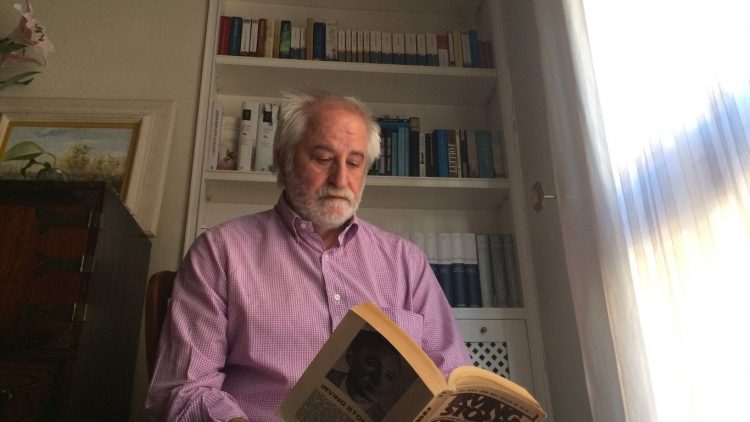 Rafael Larraz leyendo un libro de Irvin Stone frente a alguno de los libros de su biblioteca incluidas una colección de enciclopedias